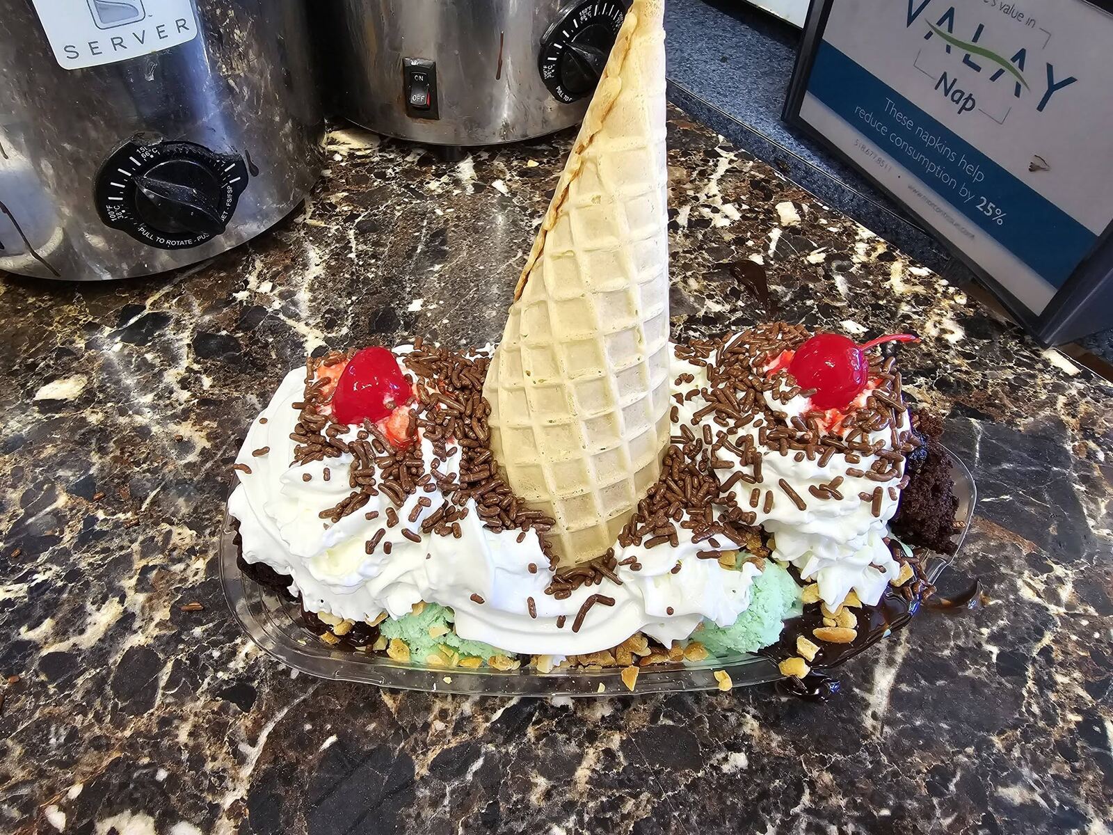 A large Blueberry Hill banana split with whipped cream, chocolate sprinkles, cherries and a waffle cone